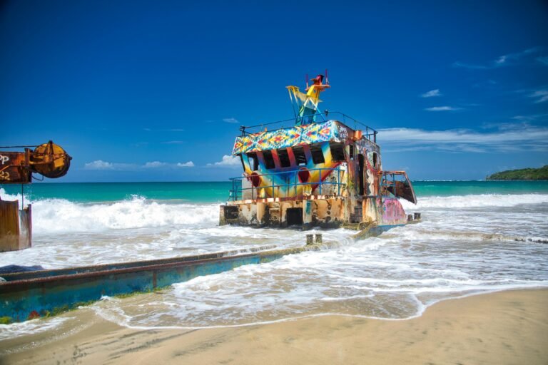 Cotizar servicios de translados 7 Colorful shipwreck on the sandy shores of Limón, Costa Rica, under a clear blue sky.